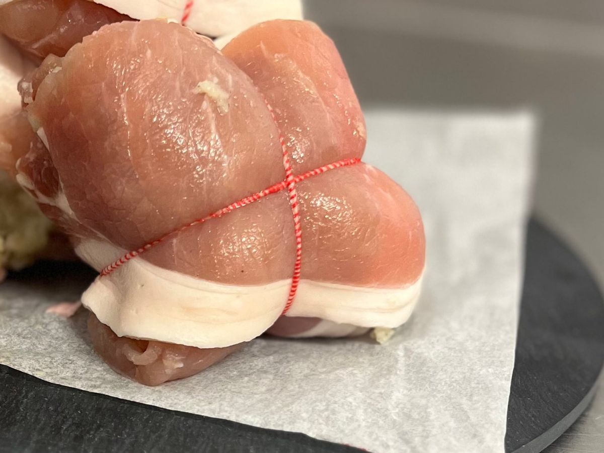 Close-up of a stuffed pork roll tied with red butcher’s string